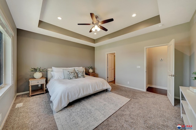 carpeted bedroom featuring a tray ceiling and ceiling fan