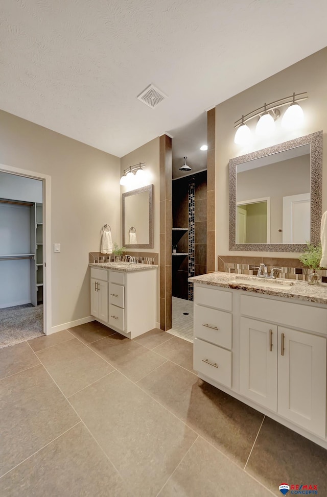 bathroom with tile patterned floors, a shower, and vanity