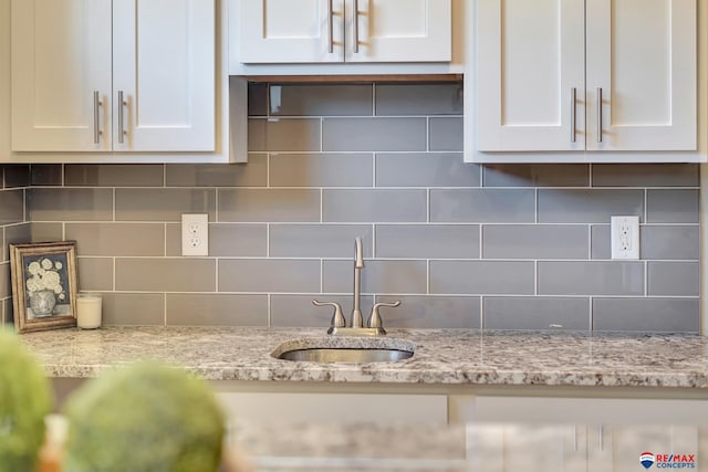 kitchen featuring decorative backsplash, white cabinetry, and light stone countertops