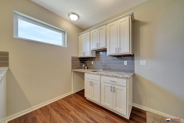 kitchen featuring white cabinetry, sink, light stone countertops, tasteful backsplash, and light hardwood / wood-style floors