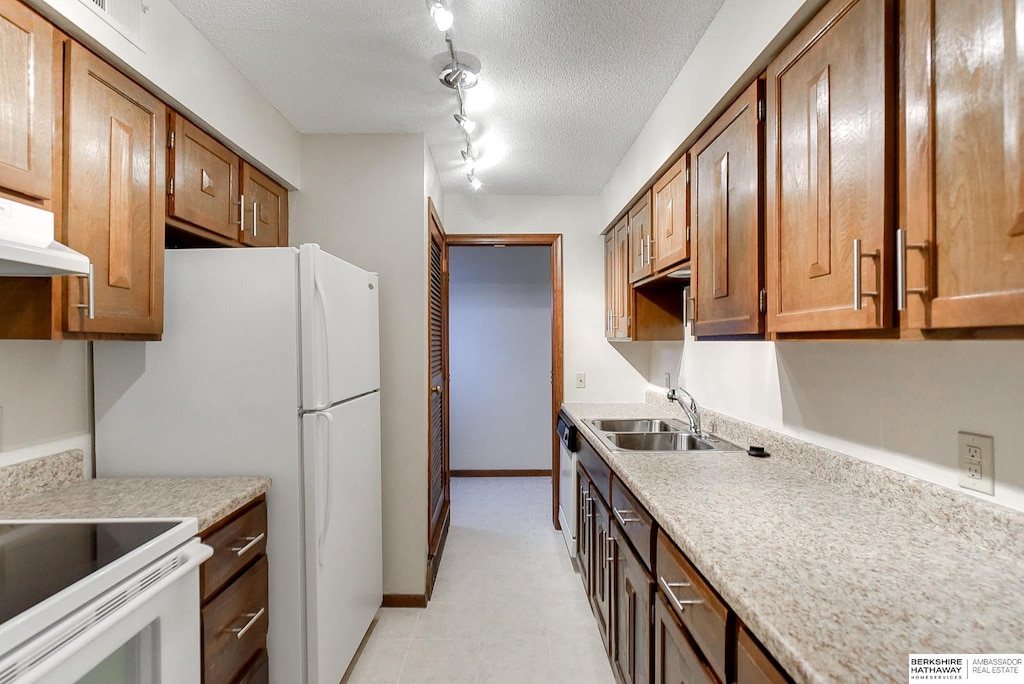 kitchen featuring rail lighting, white appliances, a textured ceiling, extractor fan, and sink