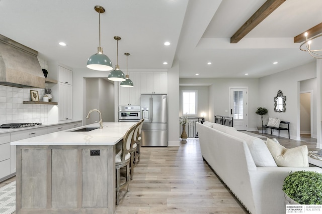 kitchen featuring a large island with sink, white cabinets, and stainless steel appliances