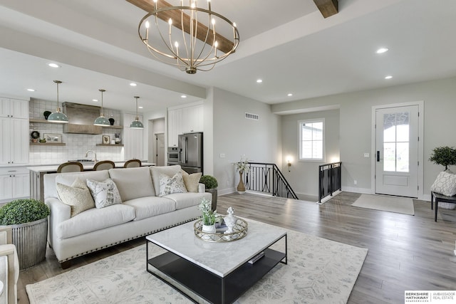 living room featuring wood-type flooring, a notable chandelier, and sink