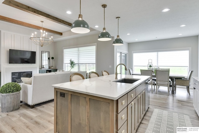 kitchen with pendant lighting, sink, an island with sink, beamed ceiling, and a healthy amount of sunlight