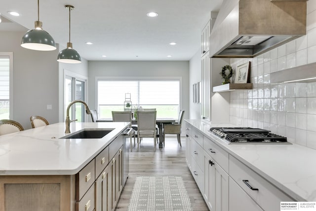 kitchen featuring custom range hood, white cabinetry, a kitchen island with sink, and sink