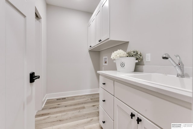 washroom featuring light hardwood / wood-style floors, cabinets, sink, and hookup for a washing machine