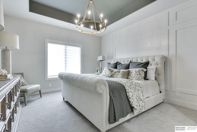 carpeted bedroom with a raised ceiling and an inviting chandelier