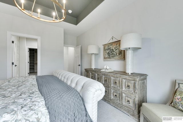 carpeted bedroom featuring a notable chandelier and a tray ceiling