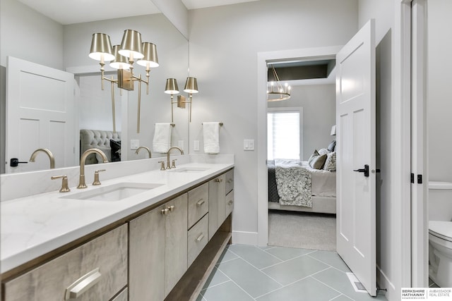 bathroom with tile patterned floors, toilet, vanity, and a notable chandelier