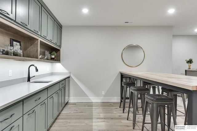 kitchen featuring wood counters, light wood-type flooring, green cabinets, and sink