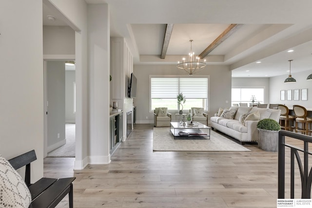 living room featuring beam ceiling, light hardwood / wood-style flooring, and a chandelier