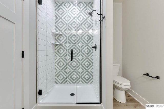 bathroom featuring hardwood / wood-style flooring, toilet, and a shower with shower door