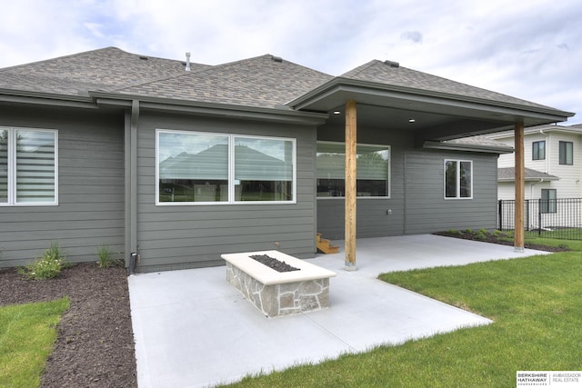 rear view of house with a fire pit, a patio area, and a lawn