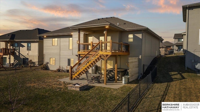 back house at dusk with a patio area, a yard, and a wooden deck