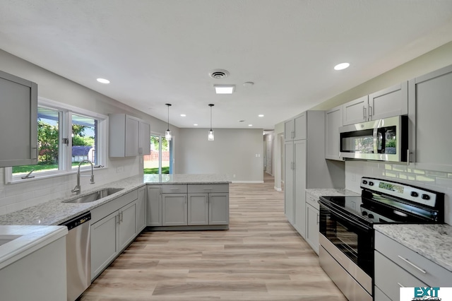 kitchen with sink, gray cabinets, light stone countertops, light hardwood / wood-style floors, and stainless steel appliances