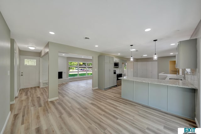 kitchen featuring gray cabinetry, sink, hanging light fixtures, a fireplace, and stainless steel appliances