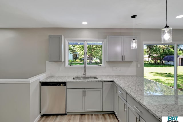 kitchen featuring light stone countertops, stainless steel dishwasher, sink, gray cabinets, and hanging light fixtures