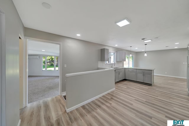 kitchen with kitchen peninsula, gray cabinets, light hardwood / wood-style flooring, and sink