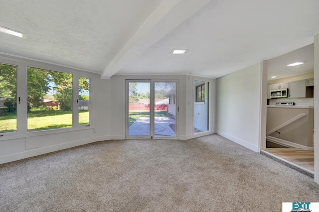 carpeted empty room with beam ceiling