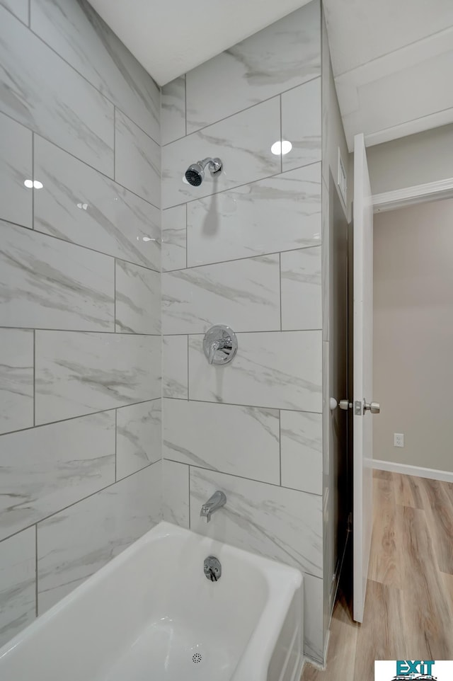 bathroom with hardwood / wood-style floors and tiled shower / bath combo