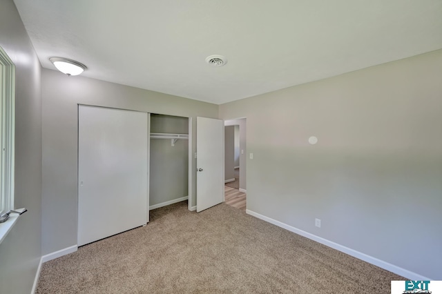 unfurnished bedroom with light carpet and a closet