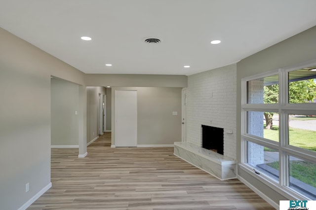 unfurnished living room featuring a large fireplace and light hardwood / wood-style floors