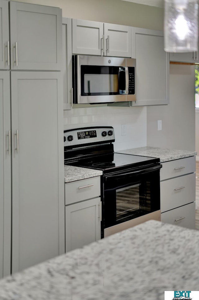 kitchen with light stone countertops and appliances with stainless steel finishes