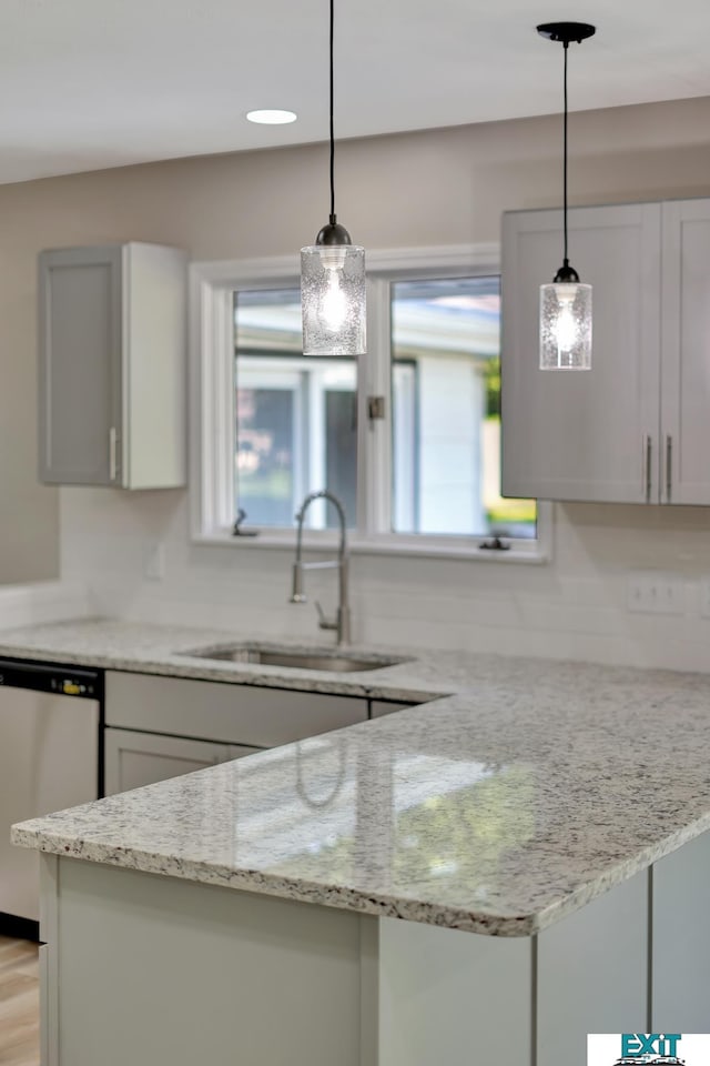 kitchen with light stone countertops, hanging light fixtures, and stainless steel dishwasher