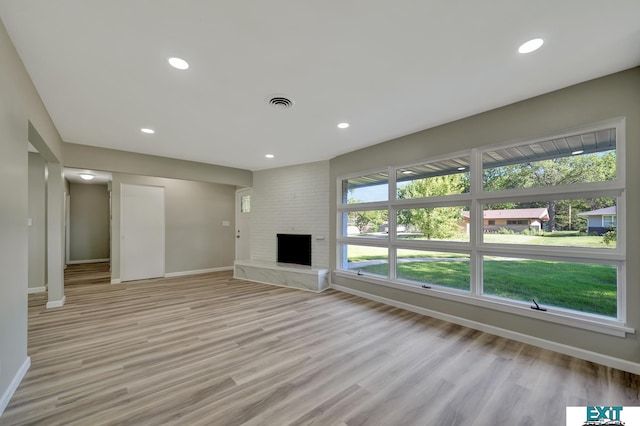 unfurnished living room with a fireplace and light wood-type flooring