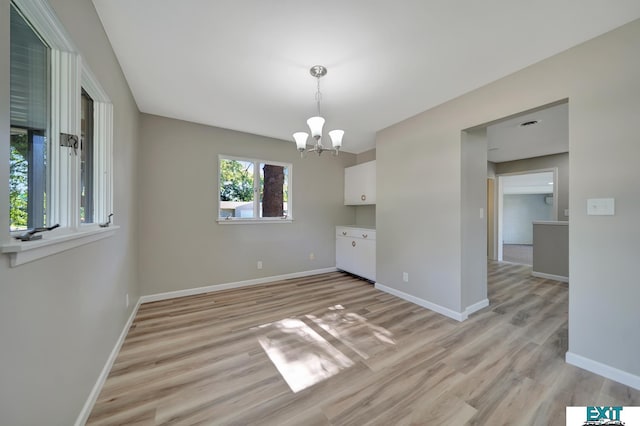 spare room featuring light wood-type flooring and an inviting chandelier