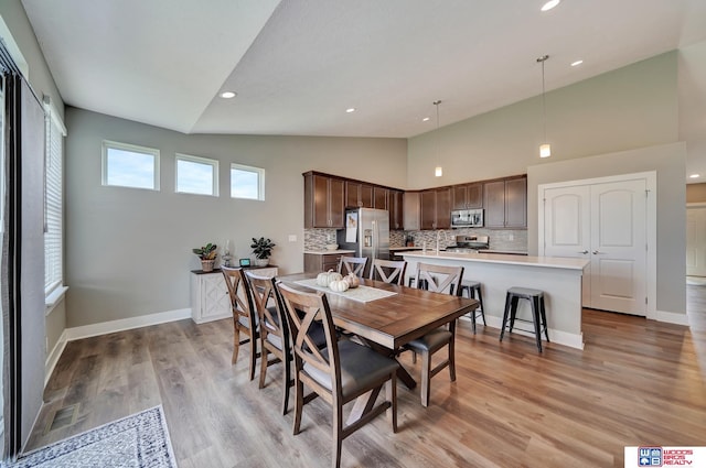 dining room featuring light wood-type flooring, high vaulted ceiling, and plenty of natural light