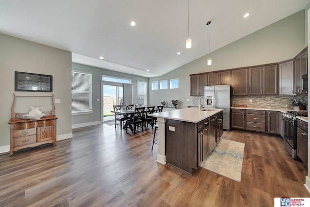 kitchen featuring a center island with sink, hanging light fixtures, dark brown cabinets, dark hardwood / wood-style flooring, and stainless steel appliances