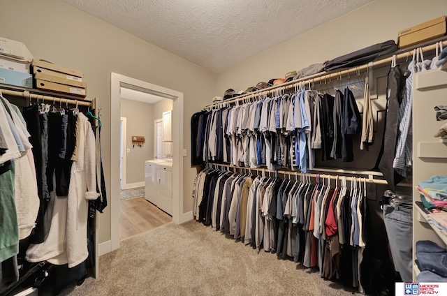 spacious closet featuring washer and clothes dryer and light colored carpet