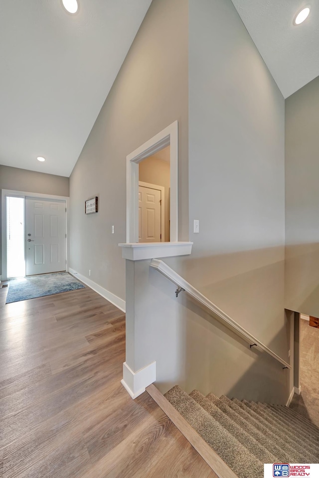 stairway with hardwood / wood-style flooring and high vaulted ceiling