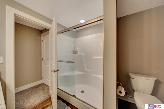 bathroom with wood-type flooring, toilet, and a shower with door