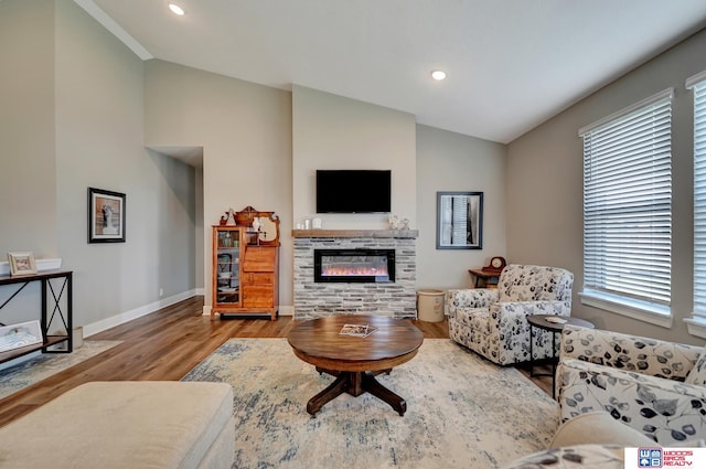 living room featuring a stone fireplace, light hardwood / wood-style flooring, and vaulted ceiling