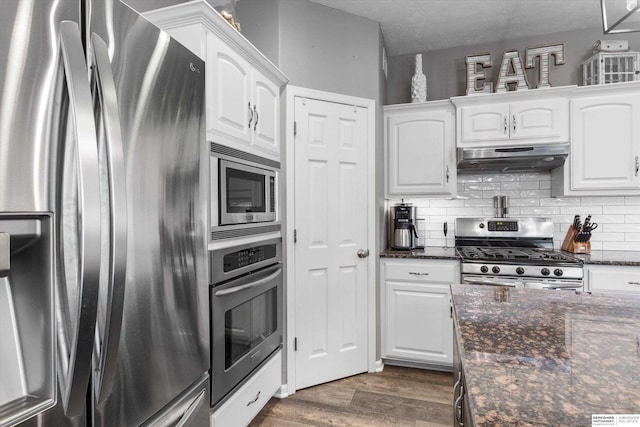 kitchen with white cabinets, stainless steel appliances, and dark stone counters