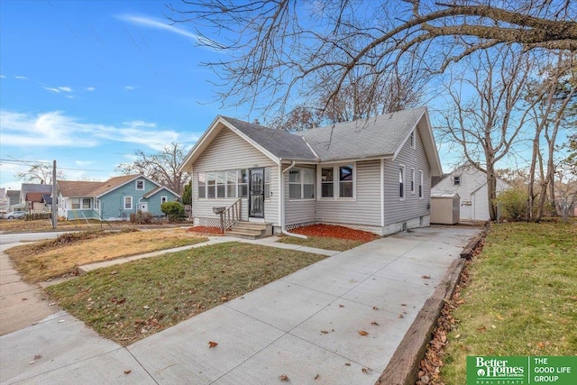 bungalow-style home with a front lawn and an outdoor structure