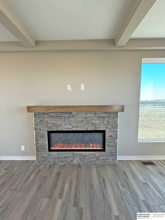 interior details with beam ceiling, a fireplace, and hardwood / wood-style floors