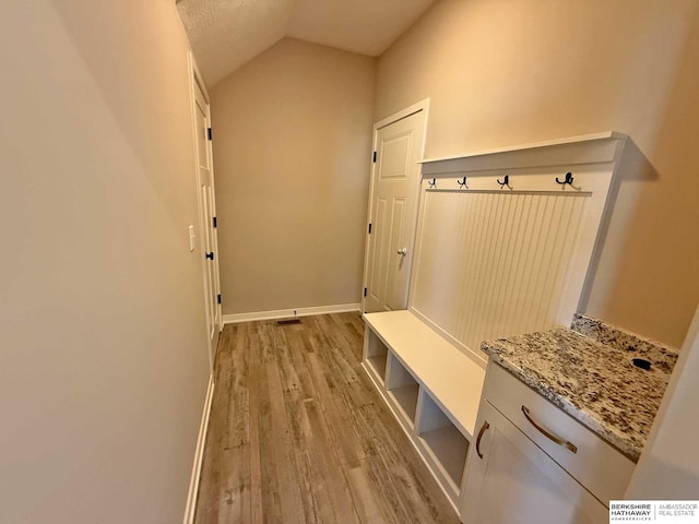 mudroom featuring light wood-type flooring, a textured ceiling, and vaulted ceiling