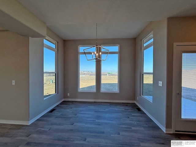 unfurnished dining area featuring plenty of natural light, dark hardwood / wood-style floors, and a notable chandelier