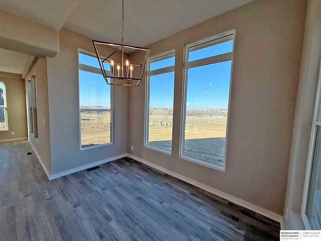 unfurnished dining area featuring a chandelier, wood-type flooring, and a wealth of natural light