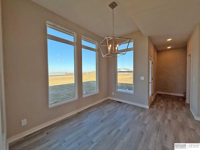 unfurnished dining area featuring wood-type flooring and an inviting chandelier