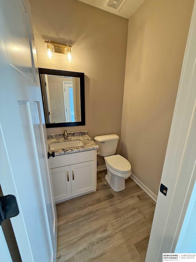 bathroom featuring wood-type flooring, vanity, and toilet