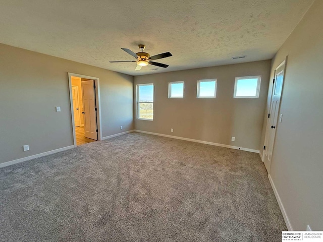 unfurnished bedroom featuring multiple windows, a textured ceiling, light colored carpet, and ceiling fan