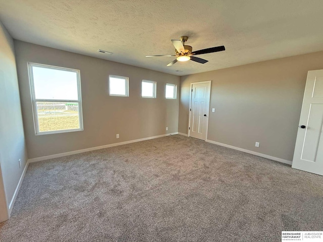 carpeted empty room featuring ceiling fan and a textured ceiling