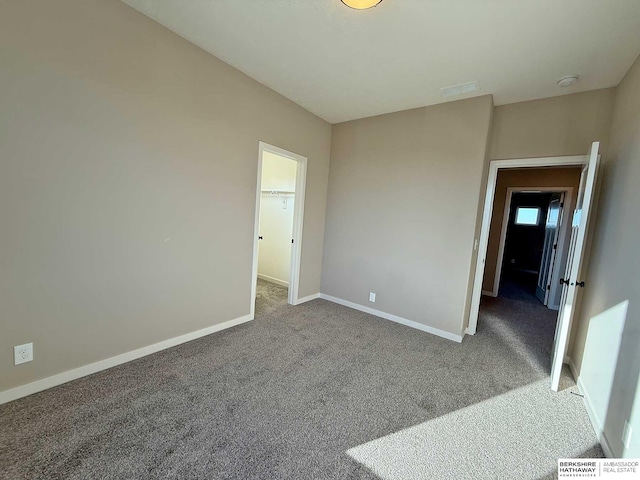 unfurnished bedroom with a spacious closet, carpet floors, and a closet