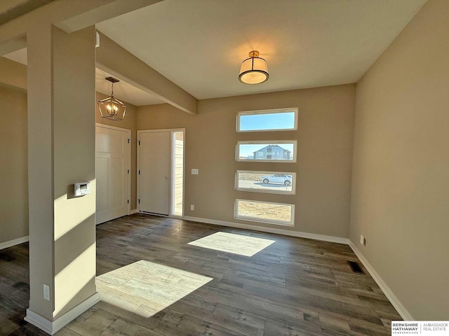 entrance foyer with beamed ceiling, a notable chandelier, and dark wood-type flooring