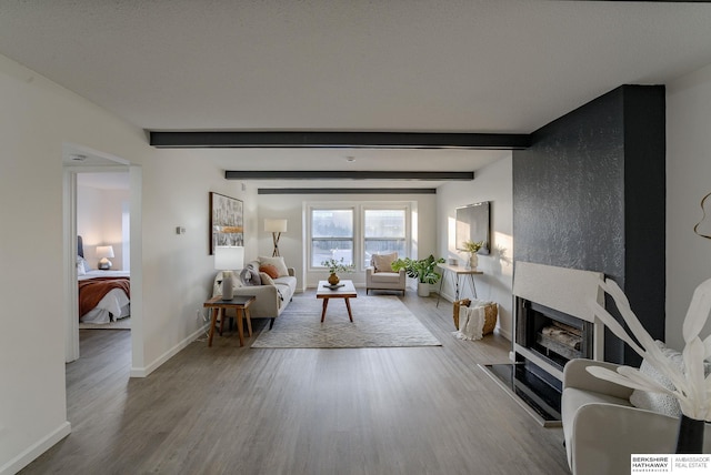 living room featuring beam ceiling, a fireplace, and light wood-type flooring