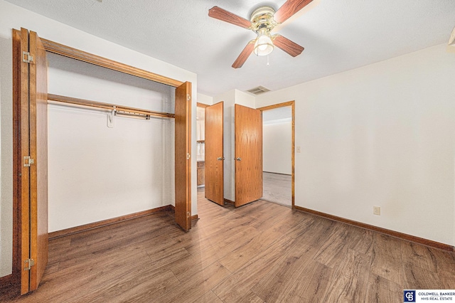 unfurnished bedroom featuring ceiling fan, a closet, and hardwood / wood-style flooring